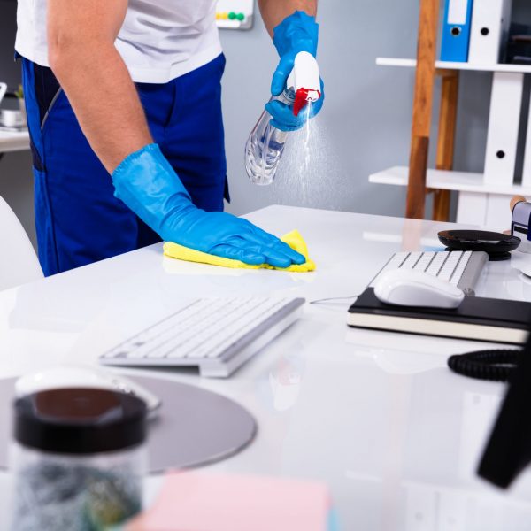 Janitor cleaning white desk in modern office